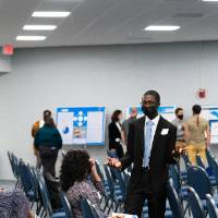 Scholar wearing mask talking with guest in the audience.